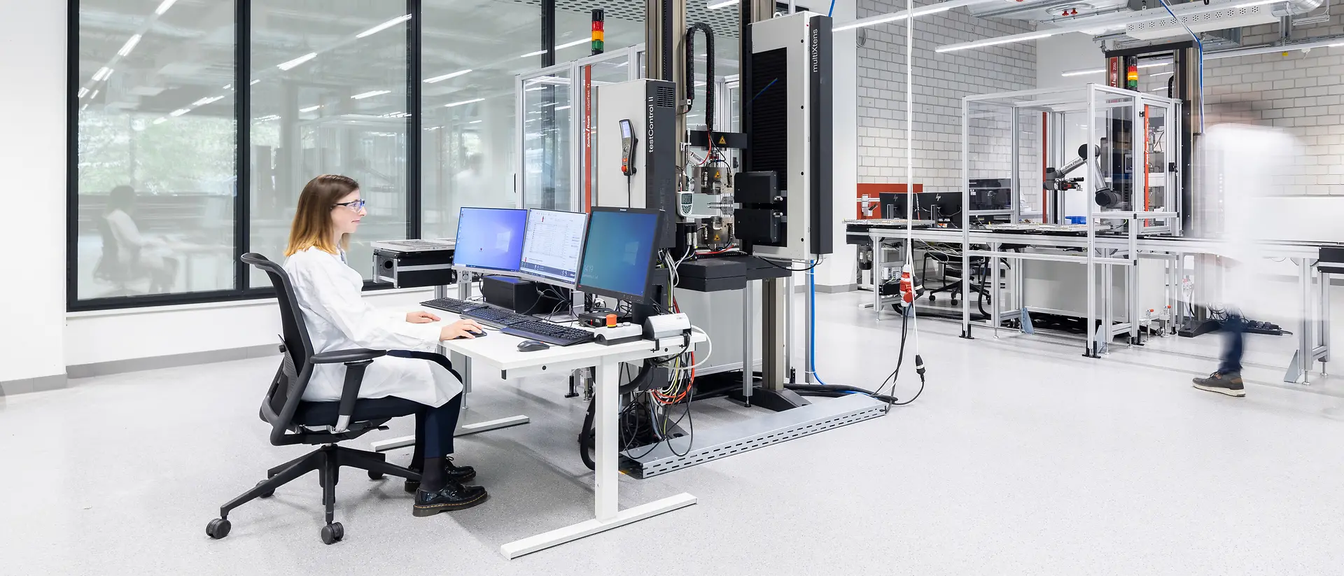 A lab technician sits at a computer operating software in the Automated Lab.