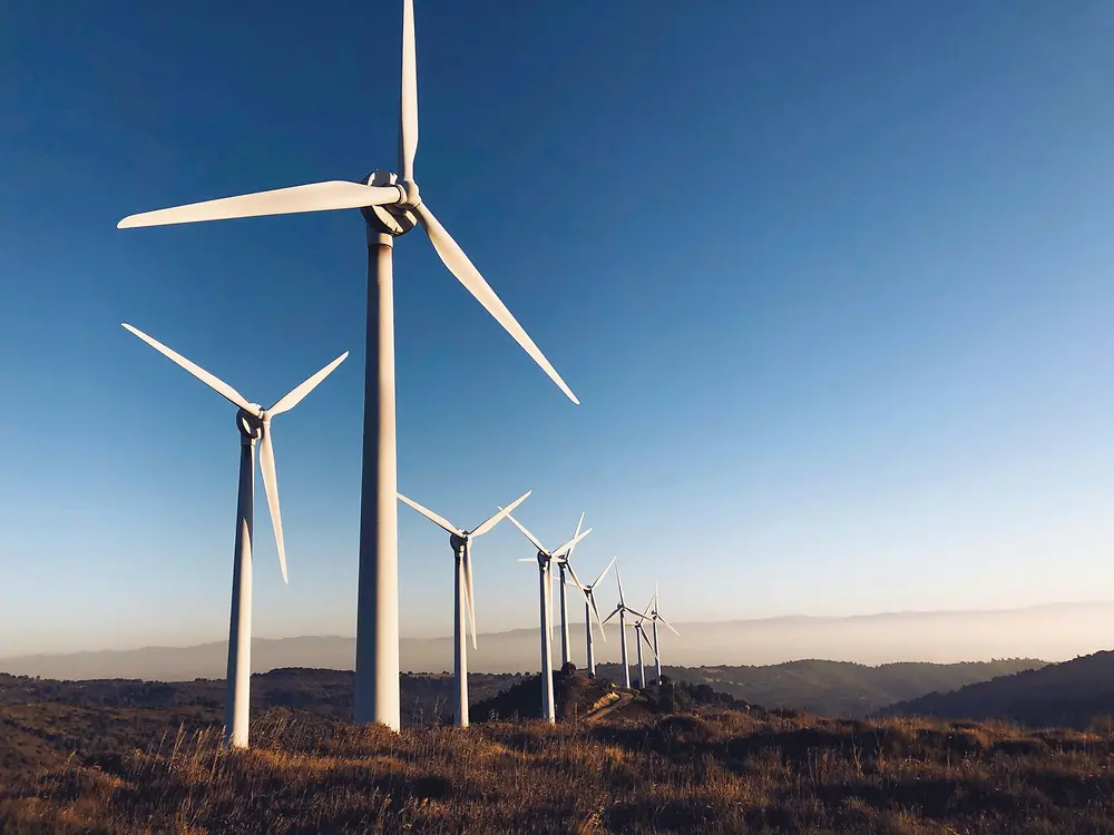 wind turbines in a hilly landscape in front of blue sky 