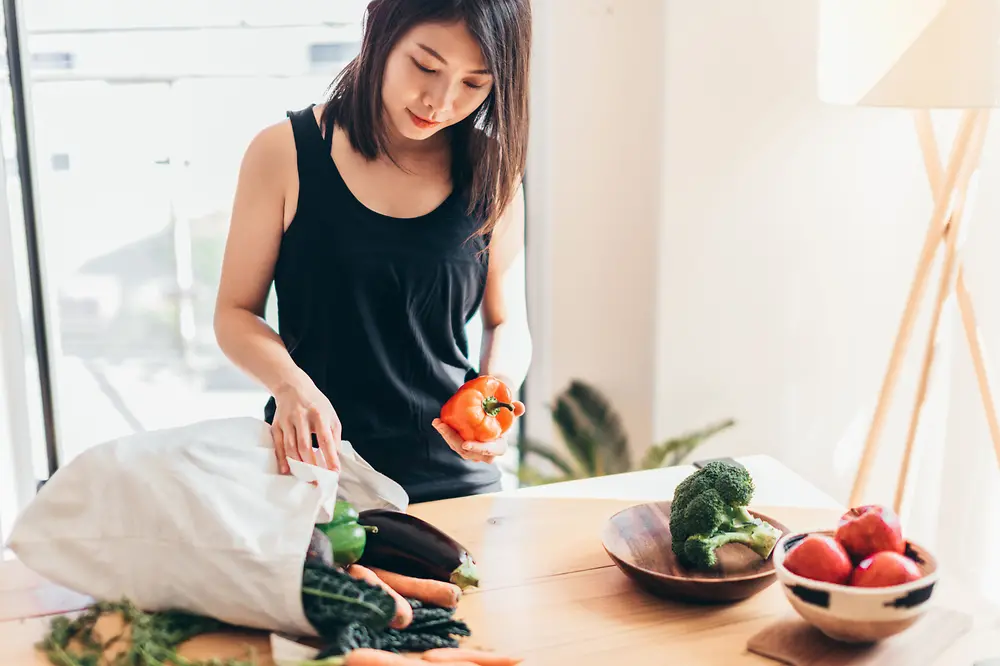 A woman unpacks her shopping from a canvas tote bag.